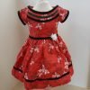 A red dress with a white floral print. It has black velvet accents and a white sateen flower.