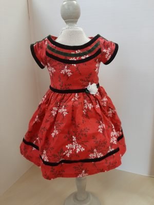 A red dress with a white floral print. It has black velvet accents and a white sateen flower.