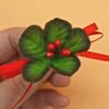 a bouquet of holly leaves and red berries tied together with a red bow