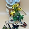 A basket, pretend butterflies, yellow faux flowers, magnifying glass on a cord, wooden flower press, and fabric net with wood handle. Excellent condition.