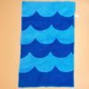 Terrycloth beach towel. Six-stripe pattern of alternating blue and light blue scalloped waves; colors are reversed on backside. Surged at edges. Dimensions 17 1/2" long by 11 1/2" wide. No marks, excellent condition.